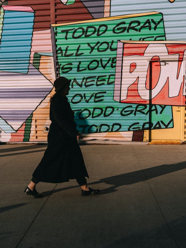 A person walking past a colorful graffiti wall